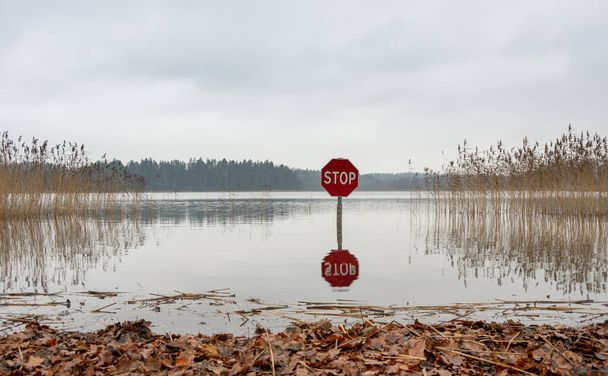 A red stop sign in the lake that prohibits the entry and at the same time measures the water - Photo, Image