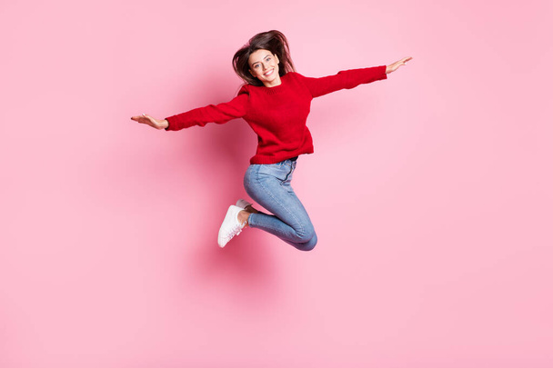 Full length body size portrait of pretty funny girl jumping high wearing casual clothes smiling keeping hands like plane isolated on pink color background - Foto, Imagem