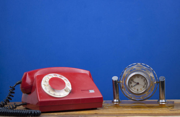 Teléfono retro giratorio sobre mesa de madera sobre pared azul en la habitación - Foto, imagen