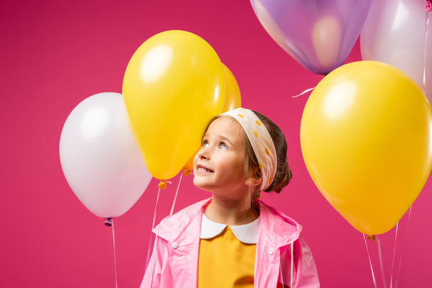 happy kid looking away near balloons isolated on crimson  - Photo, Image