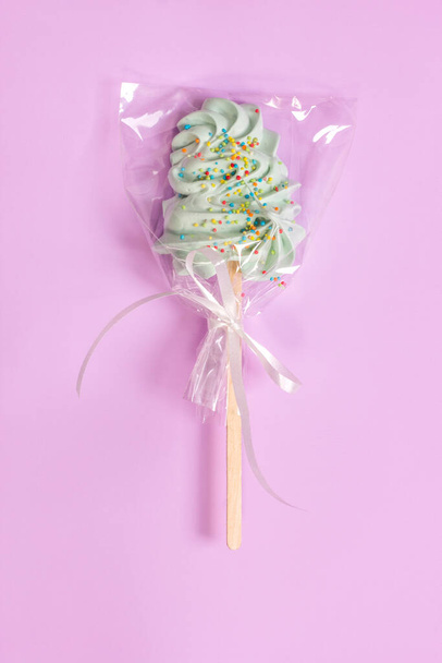Sweet lollipop in a transparent wrapper on a gentle pastel pink background. - Photo, Image