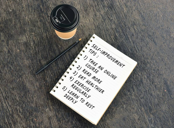 Text on notepad with disposable coffee cup wooden table - Photo, Image
