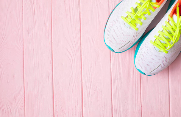 top view of pair of white sneakers on pink wooden background - Φωτογραφία, εικόνα