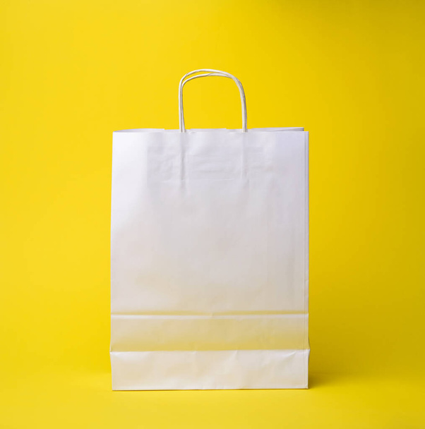bílá papírová jednorázová taška s rukojetěmi na žlutém pozadí, bez odpadu - Fotografie, Obrázek