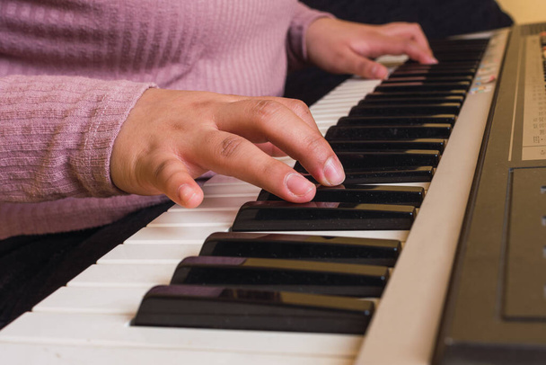δύο χέρια ενός νεαρού κοριτσιού που παίζει πιάνο με μωβ πουλόβερ - Φωτογραφία, εικόνα