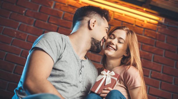 Caucásico hombre está besando a su novia mientras le da un regalo citas en día de San Valentín - Foto, imagen