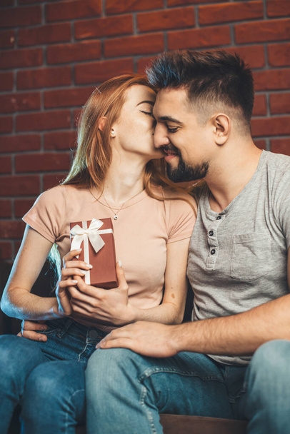 Белый мужчина целуется со своей рыжей подружкой после того, как сделал ей подарок на День Святого Валентина. - Фото, изображение