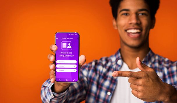 Happy Black Guy Pointing op Smartphone met geopende app voor online leren - Foto, afbeelding