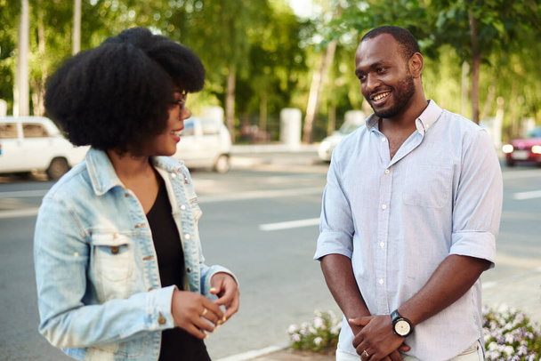 Афроамериканка і чорношкірий чоловік розповідають про новини дня, стоячи на міській вулиці. - Фото, зображення