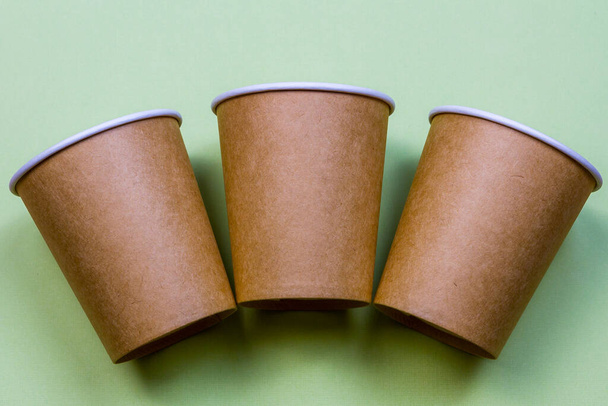 Tres vasos de papel hechos de papel eco kraft sobre el fondo verde. - Foto, imagen