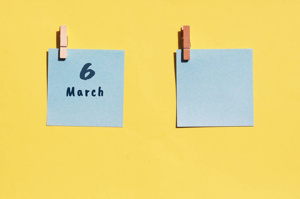 Le 6 mars. Jour de 6 mois, date du calendrier. Deux draps bleus pour écrire sur un fond jaune. Vue du dessus, espace de copie. Printemps mois, jour de l'année concept - Photo, image