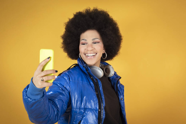 donna che parla con smartphone, sorride felice, fa selfie, vestiti urbani e cuffie, spazio copia - Foto, immagini
