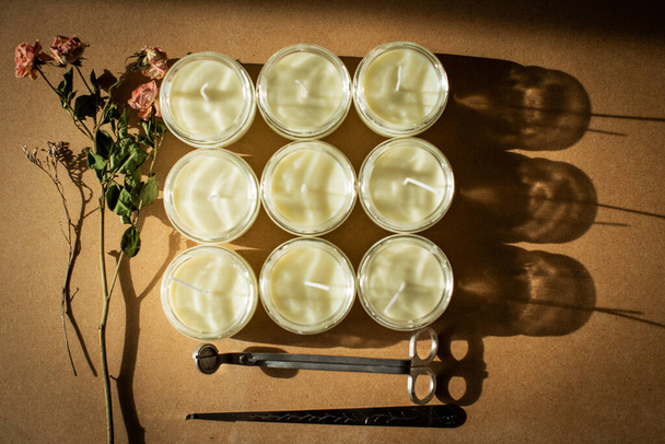houten lonten kaarsen. Handgemaakte kaars van paraffine en sojawas in glas met bloemen en blad op ambachtelijke ondergrond. Laat het los. Kaarsen maken. Bovenaanzicht. - Foto, afbeelding