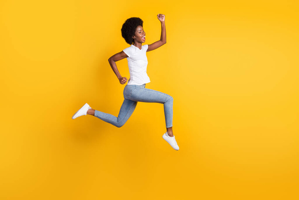 Full length body size photo of funny pretty female hipster with black skin jumping high running fast screaming loudly isolated on bright yellow color background - Foto, afbeelding