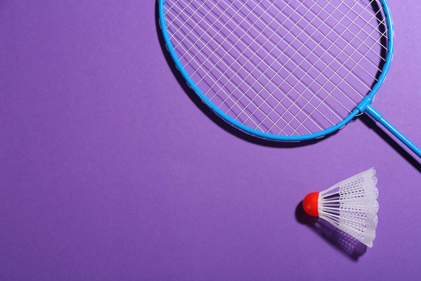 Badminton racket and shuttlecock on purple background, flat lay. Space for text - Foto, Imagen