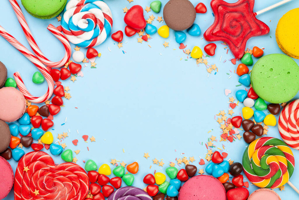 Různé sladkosti sortiment. Candy, bonbon a makaróny na modrém pozadí. Horní pohled plochý ležel s kopírovacím prostorem - Fotografie, Obrázek