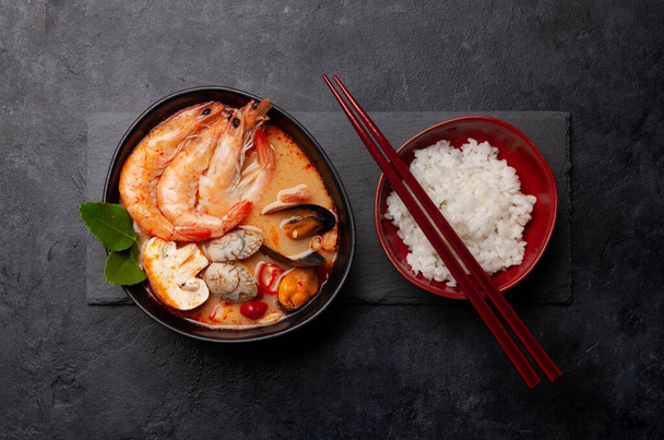 Traditional Thai soup Tom Yum kung with seafood, coconut milk and chili pepper and rice bowl. Top view flat lay - Foto, Imagen