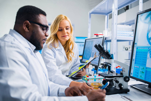 Professional team of scientists is working on a vaccine in a modern scientific research laboratory. Genetic engineer workplace. Future technology and science. - Photo, image