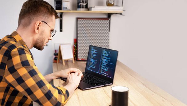Programador masculino usando el código de computadora Programas en un hogar brillante. Concepto programador Día. - Foto, imagen