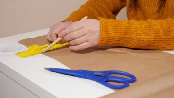 Nerozpoznatelná žena kreslí čáru perem pomocí pravítka na papír kraft - Záběry, video