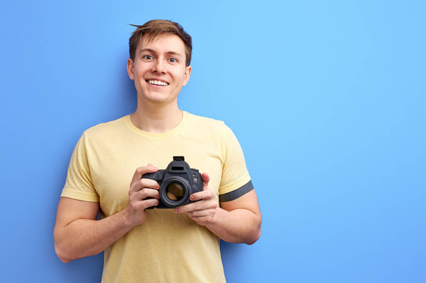 positive male photographer holding professional camera in hands - Foto, imagen