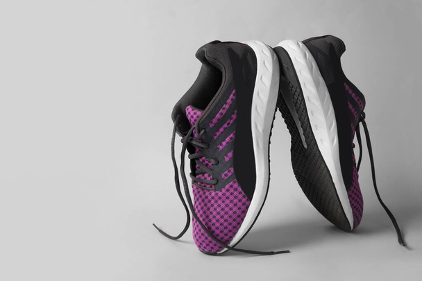 Stylish sneakers with black shoe laces on grey background - Zdjęcie, obraz