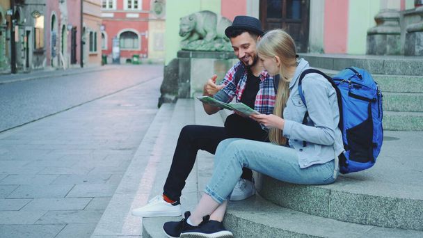 Touristenpaar sitzt auf Straßentreppen, prüft Stadtplan und diskutiert - Foto, Bild