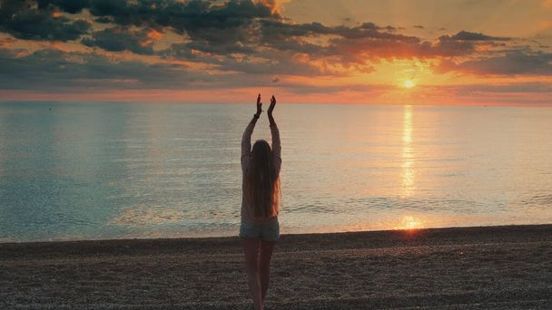 Mujer con el pelo largo caminando hacia el mar y levantando las manos - Foto, Imagen