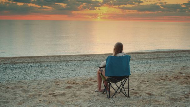 Mujer sentada en una silla de camping y tomando café - Foto, Imagen