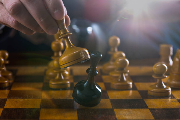 concept of strategy and business planning, businessman behind a chessboard white queen beats a black chess piece, strategy and tactics, readiness for battle, start of battle. - Zdjęcie, obraz