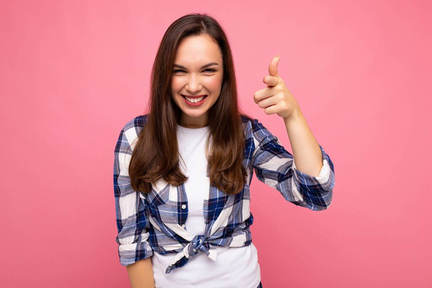 Kuvattu nuori onnellinen hymyilevä kaunis brunette nainen vilpittömiä tunteita yllään trendikäs check paita eristetty vaaleanpunainen tausta tyhjä tila - Valokuva, kuva