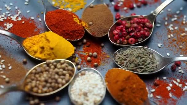 Przyprawy w tle. Indyjskie i azjatyckie przyprawy spożywcze na łyżkach i ciemnym tle. Curry, pieprz, chili jako składniki kuchni indyjskiej - Materiał filmowy, wideo