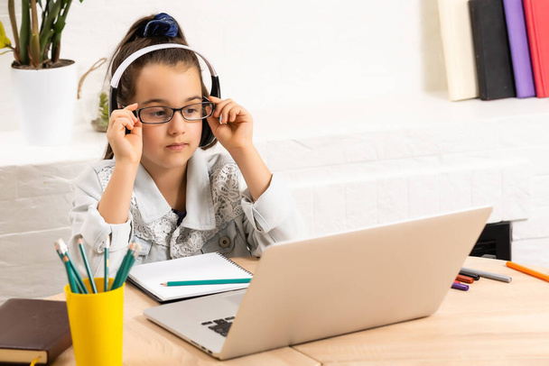 Bambino online. Una bambina utilizza una video chat portatile per comunicare l'apprendimento mentre è seduta a casa. - Foto, immagini