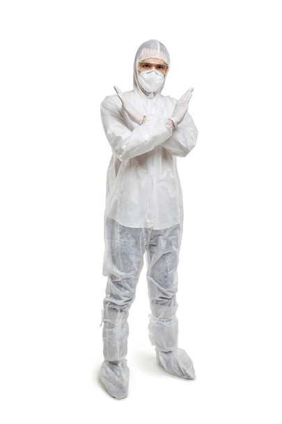 Male doctor in chemical protection in full height shows no, hands crossed. - 写真・画像