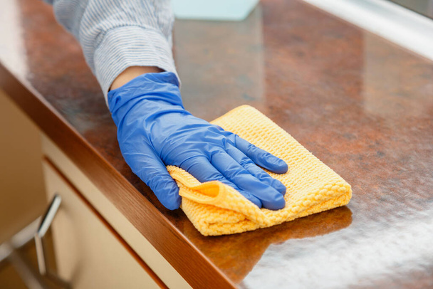 Woman wiping table countertop in kitchen by wet cloth rag. Female charwoman hand cleaning disinfect office home restaurant surfaces. - Foto, imagen