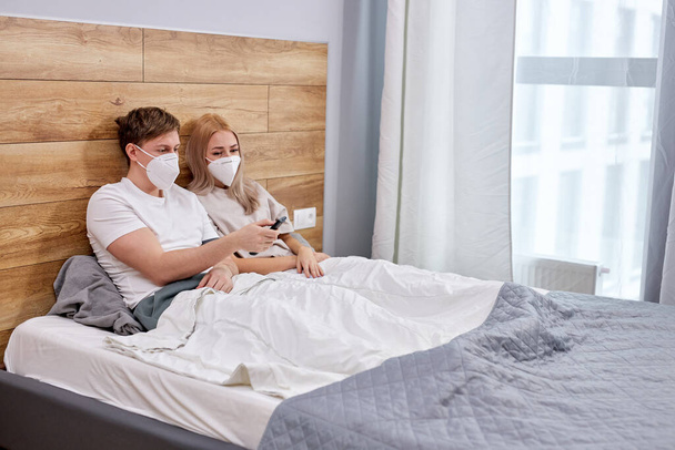 side view on young couple is quarantined at home, watching tv - 写真・画像