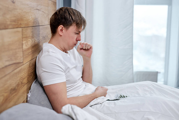 joven que sufre de covid-19 coronavirus síntomas acostado en la cama en casa - Foto, imagen