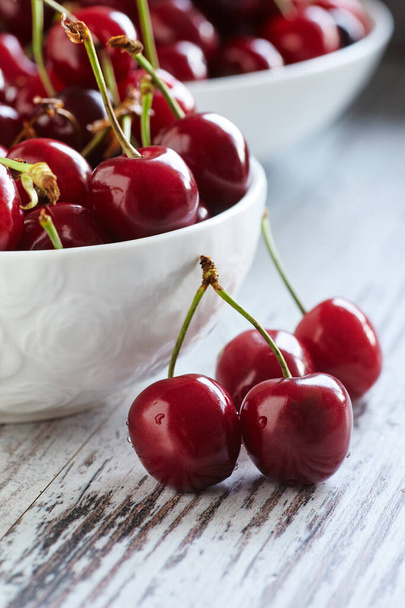 Cherries in a white bowl on white wooden table - Photo, Image