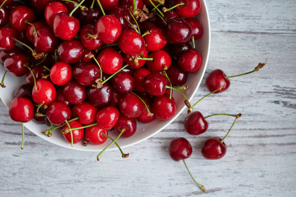 Cherries in a white bowl on white wooden table - Foto, immagini