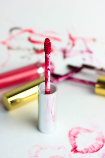 Lustro de lábio rosa líquido em um tubo em uma mesa branca flatlay, fundo borrado. Uma impressão de um beijo no papel. Cosméticos decorativos para meninas. Foto de alta qualidade - Foto, Imagem