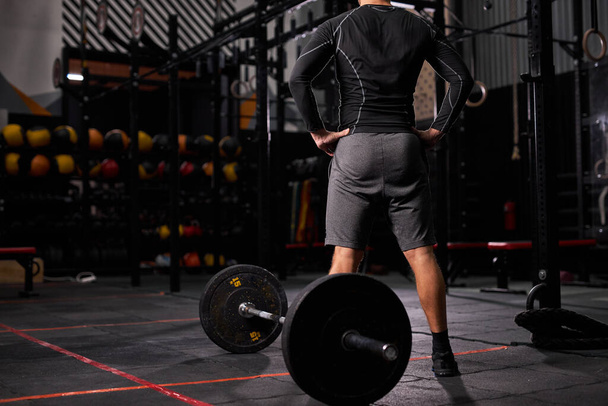 rear view on sportsman standing near barbell - Photo, image