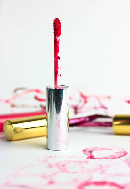 Flüssiger roter Lipgloss in einer Röhre auf einer weißen Tischplatte, viele Glossen, verschwommener Hintergrund. Dekorative Kosmetik für Mädchen. Hochwertiges Foto - Foto, Bild