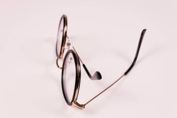 Seitenansicht von Brillen, die senkrecht liegen, wobei ein Arm leicht ausgestreckt und der andere gefaltet ist - Foto, Bild