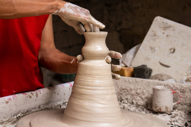 Człowiek robi wyroby ceramiczne na koło garncarskie w tradycyjnej fabryce w mieście Raquira znajduje się w departamencie Cundinamarca w Kolumbii - Zdjęcie, obraz