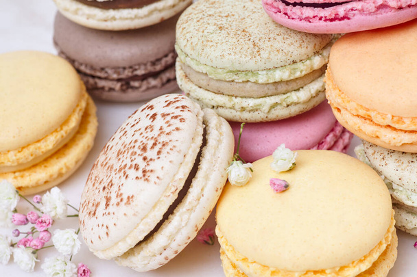 Few colored macarons and flowers on a white background - Foto, imagen