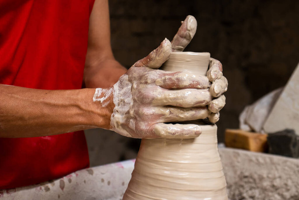 Hombre haciendo artículos cerámicos sobre la rueda de alfarero en una fábrica tradicional en la ciudad de Raquira ubicada en el departamento de Cundinamarca en Colombia - Foto, Imagen