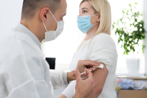 Coronavirus covid-19 aşısı ile Coronavirus covid-19 aşısı için beyaz adamın koluna aşı enjekte eden tıbbi personelin eli., - Fotoğraf, Görsel