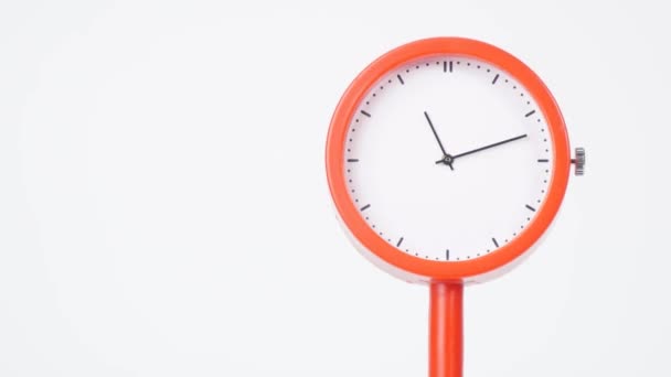 Modern orange clock showing the passage of time. Fast clockwise rotation on white background. - Πλάνα, βίντεο