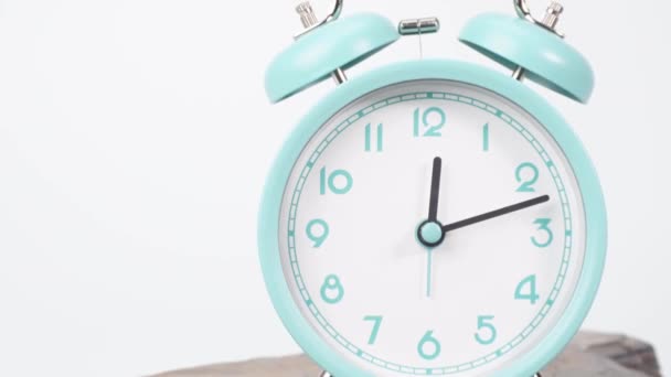 Tijd verstrijkt, de blauwe wekker zegt de tijd. Snelle rotatie met de klok mee op witte achtergrond. - Video