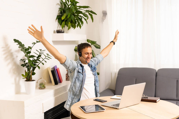 Привабливий кавказький бізнесмен, що веде онлайн розмову за допомогою ноутбука та навушників на офісному столі
 - Фото, зображення